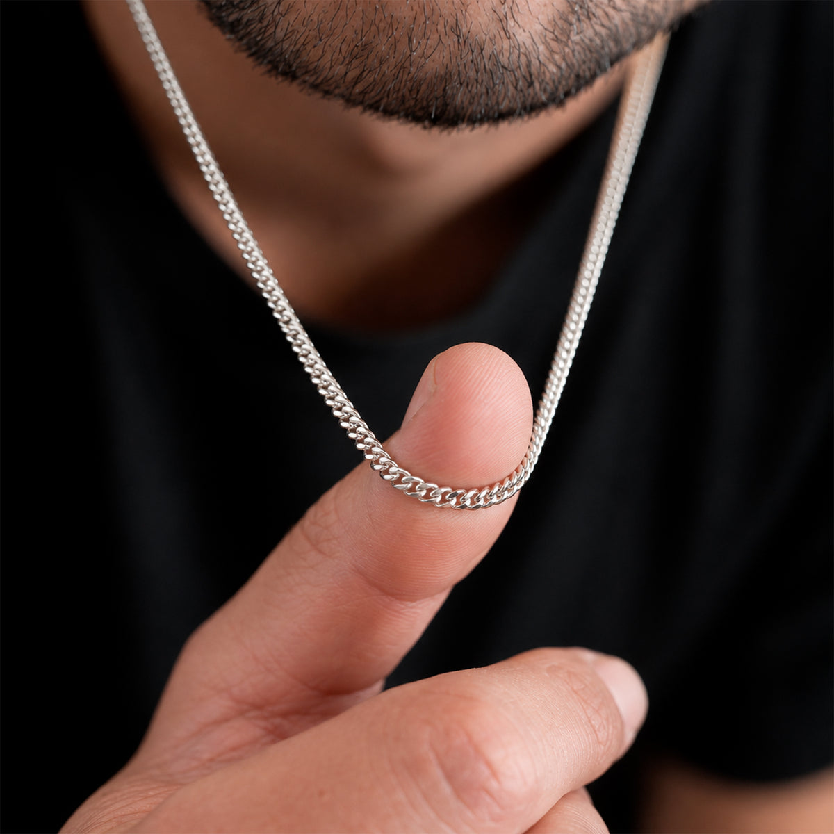 Hombre sosteniendo sobre su dedo una cadena Cuban Link de 3 mm en Plata .925, mostrando el grosor real de los eslabones cubanos y su proporción respecto a la mano.